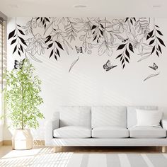 a living room with a white couch and wall decals on the walls, along with a potted plant