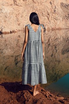 Summer days are made for mooching around and we think this gorgeous tiered khadi cotton dress is the perfect dress to do that in! We love the comfy silhouette and shoulder tie-ups and playful gingham print. Model: 5'9' and wearing a size small Pre-order info: This piece will be made to order and delivered in roughly 2-3 weeks from placing the order with us. If you need it sooner, please let us know as we may be able to expedite your order. Product details Made from Khadi cotton The top bodice is Gingham Tiered Dress For Picnic, Gingham Dress With Ruffle Hem For Vacation, Plaid Cotton Tiered Dress, Linen Gingham Dress For Daywear, Gingham Linen Dress For Daywear, Gingham Dress With Tie Straps For Beach, Beach Dress With Gingham Print And Tie Straps, Casual Cotton Maxi Dress For Picnic, Gingham Cotton Dress With Ruffle Hem