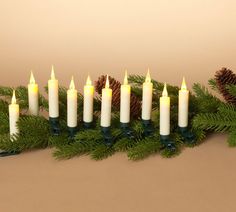 a group of lit candles sitting next to pine cones