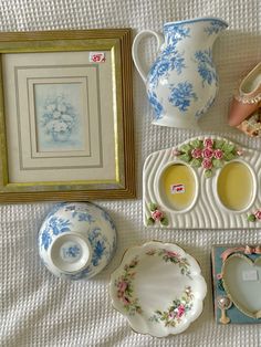 there are many plates and cups on the bed with pictures around them, including one for tea