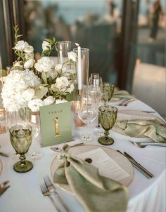 the table is set with white flowers and silverware