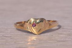 This stunning piece, known as The Heartfelt Ruby, features a captivating natural ruby set at the center of a heart motif. The natural ruby adds a touch of color and elegance, making it a delightful piece for any collection. The ring is crafted in yellow gold and is currently a finger size 4 but can be adjusted to any finger size for an additional charge upon request, ensuring a perfect fit. Love this piece, but don't have the money to spend right now? We offer FREE layaway on every item in our shop. With just 20% down, take one full year (interest-free) to pay off your new jewelry! There are no hidden fees or charges, ever. For more information on our layaway policy, please contact us. Each piece has been hand-selected and meticulously identified and graded by a Graduate Gemologist who has Gold Statement Rings, Heart-shaped Ruby Ring For Formal Occasions, 14k Gold Heart-shaped Ruby Ring For Promise, 14k Gold Heart-shaped Ruby Promise Ring, Heart-shaped Yellow Gold Ruby Ring, Yellow Gold Heart-shaped Ruby Ring, Heart-shaped Ruby Ring In Yellow Gold, Heart Shaped Ruby Ring In Yellow Gold, Ruby Heart Cut Birthstone Jewelry