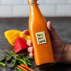 a hand holding a bottle of pesto sauce next to peppers and lemons on a counter