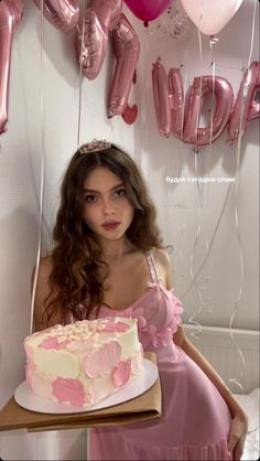 a woman in a pink dress is holding a cake with balloons around her and the cake has been cut into pieces