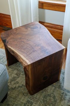 a wooden table sitting on top of a rug next to a window with curtains behind it