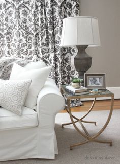 a living room with a white couch and black and white curtains