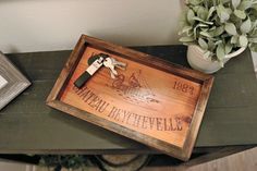 a bottle opener sitting on top of a wooden tray next to a potted plant