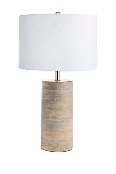 a table lamp with a white shade on it and a gold metal base in front of a white background