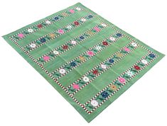 a green area rug with flowers and stripes on the bottom, in front of a white background