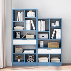 a blue bookshelf filled with lots of books next to a white rug on top of a hard wood floor