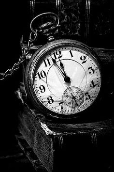 black and white photograph of an old pocket watch on a stack of books with chains