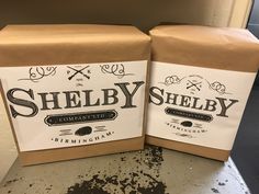 two brown boxes sitting on top of a counter next to each other, with the words shelby written on them