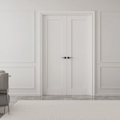 an empty white room with two chairs and a door in the wall that leads to another room