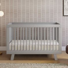 a baby's crib in the corner of a room with a chair and lamp