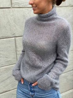 a woman wearing a gray turtle neck sweater