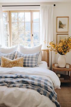 a bed with blue and white checkered comforter in front of a large window