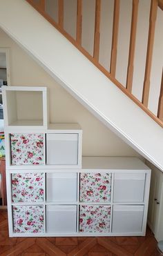 an under stairs storage unit with floral wallpaper on the bottom and bottom drawers below