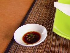 a white bowl filled with food sitting on top of a table next to a green container