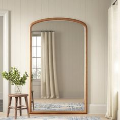 a large mirror sitting on top of a wooden floor next to a chair and table