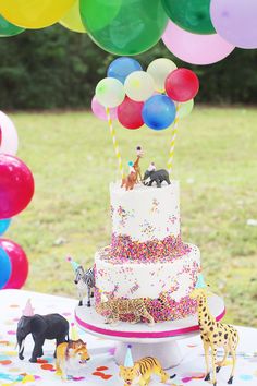 a birthday cake with balloons and animals on it