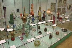 there are many vases on display in the glass case