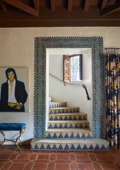 a blue and white tiled staircase leading up to a window with a painting on the wall