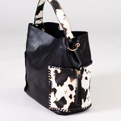 Who doesn't love cow print?! This baby is not only beautiful, but it's roomy too! Featuring two large exterior pockets, this bag has all the space you need for a day out. 11.5"h x 16"w, snap closure Wildest Dreams, Days Out, Cow Print, The Space, Black Handbags, Snap Closure, Bucket Bag, Cow, Exterior