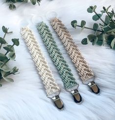 three crocheted lanyards on white fur with green plants in the background