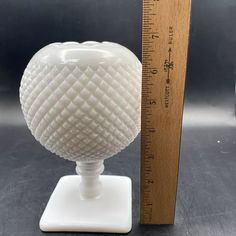 a white vase sitting next to a ruler