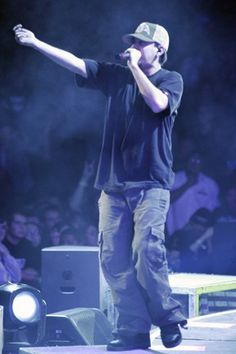 a man standing on top of a stage with his arms out in the air while holding a microphone