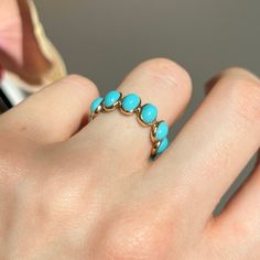 a woman's hand with a gold ring and turquoise stones on the middle finger