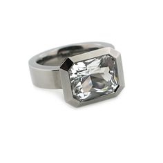 This ring has a 12mm x 10mm custom radiant cut, rock crystal which is approximately 5 carats. It is bezel set in polished silver with black rhodium finish. The shank is solid and measures 5.5mm wide at the top by 3.5mm deep and tapers down to 2.25mm deep. It is available as a standard in full, half sizes in 6-9 and available in other sizes as a special request. It is also available in green amethyst, lavender amethyst, and blue topaz. Dimensions: Bezel 12.75mm long x 15.75mm wide x 8.75mm deep A Modern Octagon Jewelry With Bezel Setting, Modern Rings With Large Stone For Formal Events, Modern Rings With Large Stone For Formal Occasions, Modern Octagon Diamond White Ring, Modern Large Stone Jewelry For Formal Occasions, Modern Rectangular Jewelry With Bezel Setting, Modern Octagon Diamond White Jewelry, Modern Radiant Cut Bezel Set Rings, Modern Radiant-cut Jewelry With Bezel Setting