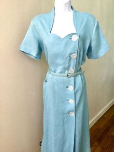 This fresh and super stylish baby blue linen 50's dress from George Hess is an awesome find! So eye catching with a flattering princess neckline and off center slight wrap front closure. It has six large plastic imitation MOP buttons ( gorgeous small shoulder pads , and short sleeves. It has one hip pocket cut to resemble the neckline. There is an added double seam down the center of the skirt . This allows the linen of the a line skirt to hold its shape. The waist has belt loops and the original belt is included . Unfortunately the belt shows its age with some rust on the buckle and discoloration.   Great vintage condition with no issues to the dress. The belt is discolored with age and the buckle is rusty.     There is no size labellooks to be Large. Please refer to the measurements belo Mop Buttons, Irish Linen, Stylish Baby, 50s Dresses, Line Skirt, 50's Dress, Dress Clothes For Women, A Line Skirt, Shoulder Pads