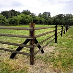 a wooden fence in the middle of a grassy field