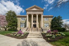 a large building with columns and flowers in front