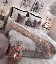 a bedroom with a large bed covered in blankets and pillows, surrounded by pictures on the wall