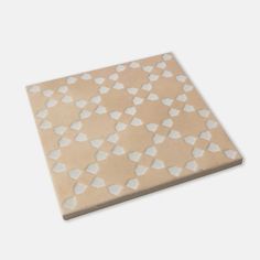 a white and beige tile with small hearts on it's side, against a gray background