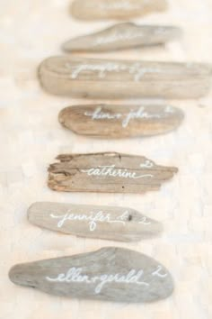 wooden signs with names are lined up on a tableclothed surface, which is decorated with wood planks