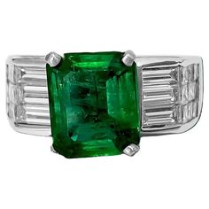 Adorn yourself in elegance with our Solid 18K White Gold Diamond and Emerald Ring, featuring a captivating 2.50 carat princess-cut emerald set in prongs. Complemented by a total of 1.00 carat diamonds, including both baguette and princess cuts, each boasting VS1 clarity and F color, this ring exudes sophistication and luxury. Crafted with 100% natural earth mined diamonds and emerald, it's a timeless piece perfect for both men and women, offering free ring resizing for a personalized fit. Key Fe Green Baguette-cut Platinum Jewelry, Luxury Green Channel Set Rings, Luxury Emerald Ring With Diamond Channel Set, Luxury Emerald Rings With Channel Set, Luxury Emerald Rings Channel Set, Luxury Emerald Diamond Ring With Channel Set, Formal Emerald Diamond Ring Channel Set, Gia Certified Green Princess Cut Diamond Ring, Gia Certified Emerald Diamond Ring Princess Cut