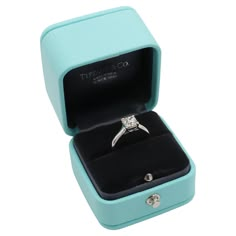 an engagement ring in a blue box with the lid open to show it's inside