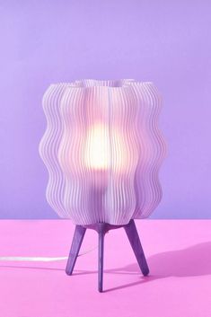 a white lamp sitting on top of a pink table next to a purple wall and floor