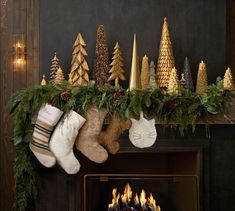 christmas stockings hanging from a mantel decorated with evergreen, pine cones and fir trees