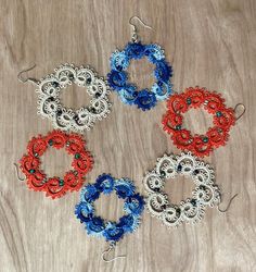 four pairs of beaded hoop earrings sitting on top of a wooden table