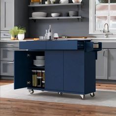 a blue kitchen island with plates and bowls on it in the middle of a wooden floor