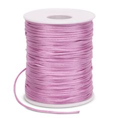 a spool of pink satin cord on a white background