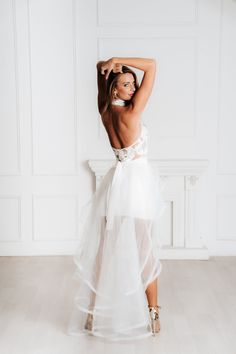 a woman in a white dress posing for the camera with her arms behind her head