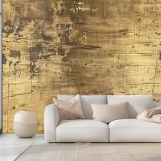 a white couch sitting in front of a wooden wall with lots of gold paint on it