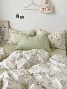 an unmade bed with white sheets and green pillow cases on the headboard above it