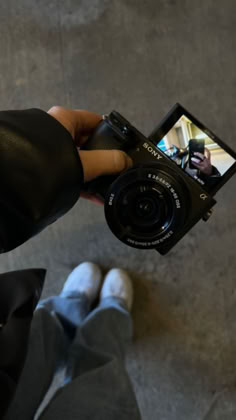 a person holding up a camera to take a photo with their feet on the ground