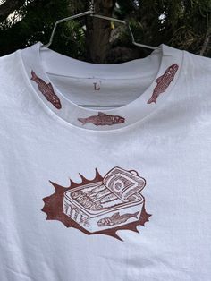 a white t - shirt with an image of a sandwich and fish on the front